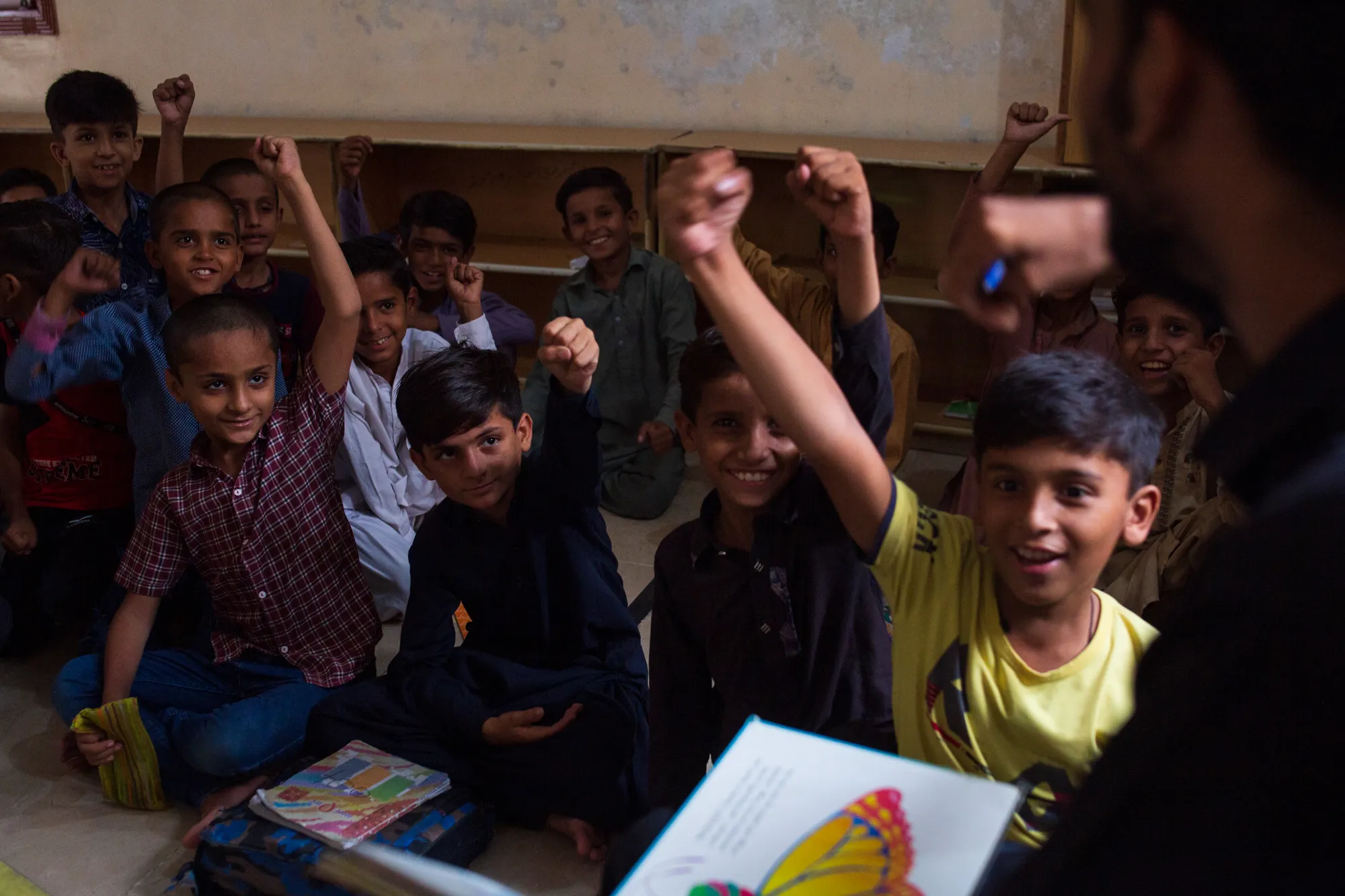 Students raising their hands in class showing their commitment to education